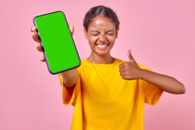 Young smiling indian woman holds out phone to camera and shows thumbs up