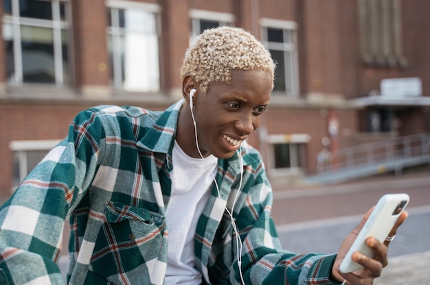 Фото Молодой улыбающийся влиятельный человек с помощью мобильного телефона записывает видео, общается онлайн на улице