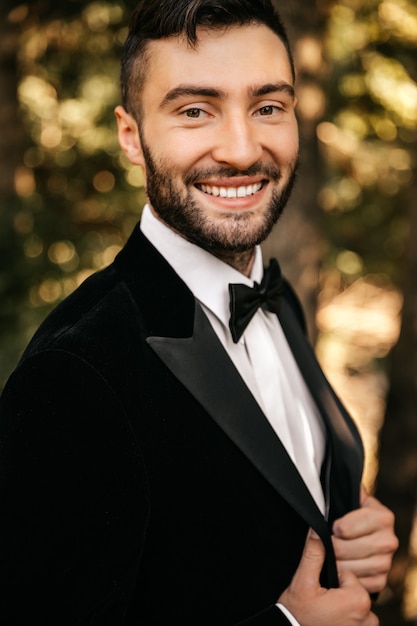 Foto giovane uomo sorridente in un abito nero con un farfallino.