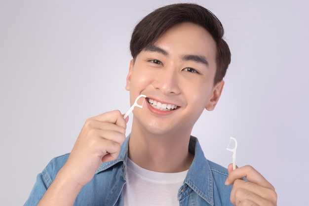 Giovane uomo sorridente azienda filo interdentale su sfondo bianco studio dentistico