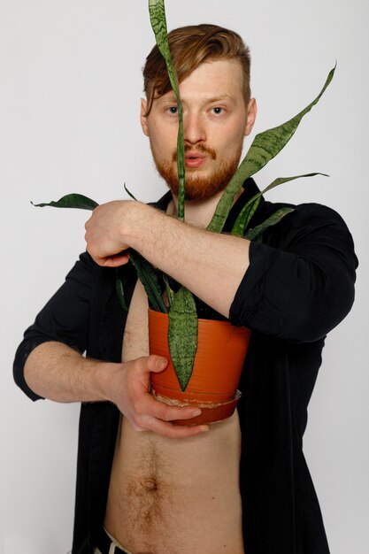 A young smiling man holds a plant in his hands