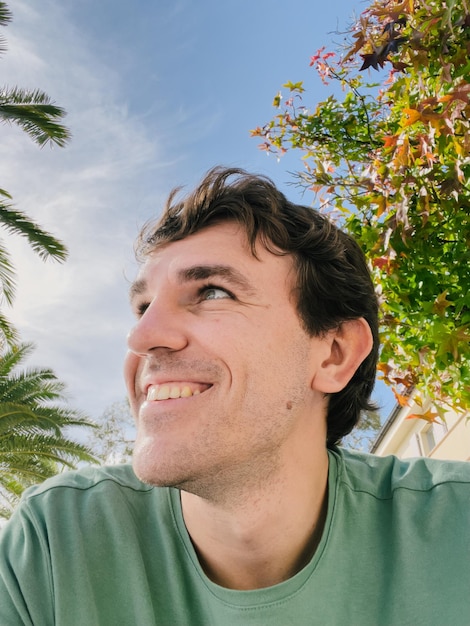 Young smiling man looking into the distance against the blue sky