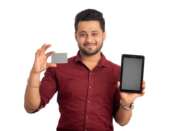 Young smiling man presenting a credit card while using a smartphone or buying online on mobile with a credit card