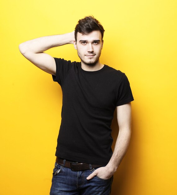 Young smiling man standing against yellow background