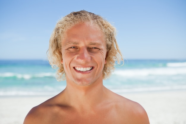 Young smiling man standing on the beach