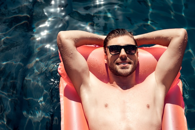 Young Smiling Man in Sunglasses on Air Mattress