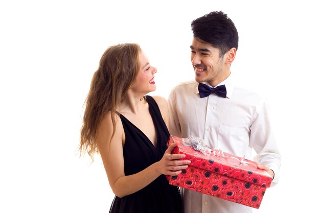 Молодой улыбающийся мужчина с черными волосами и молодая красивая женщина с длинными светлыми волосами с красным подарком