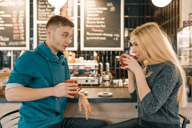 Young smiling man and woman together talking in coffee shop