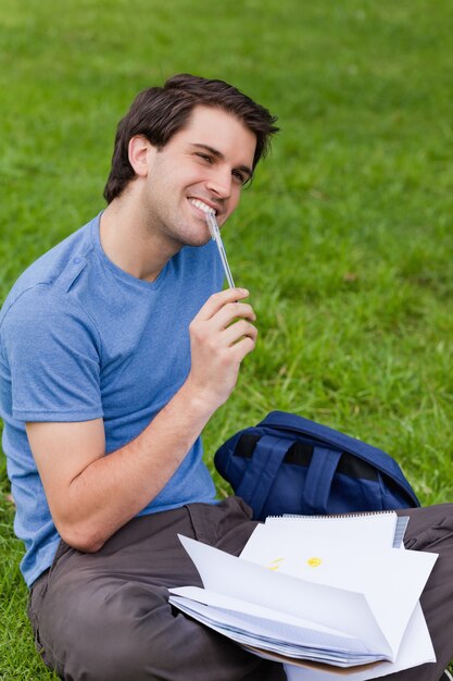 Молодой человек улыбается, сидя на траве