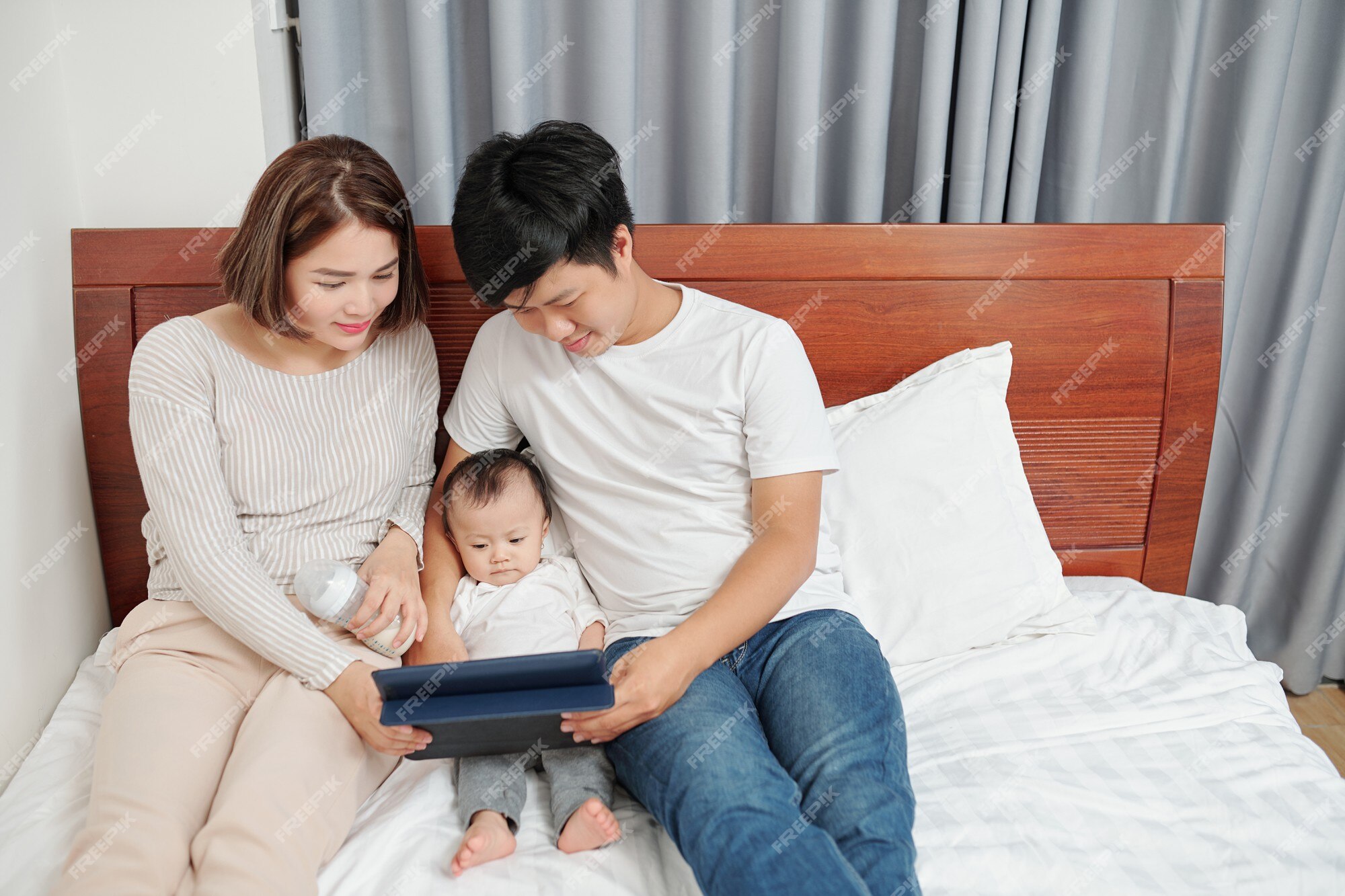 Premium Photo | Young smiling parents showing cartoon or education video on tablet computer to little baby when resting in bed Premium Photo | Young smiling parents showing cartoon or education video on tablet computer to little baby when resting in bed
