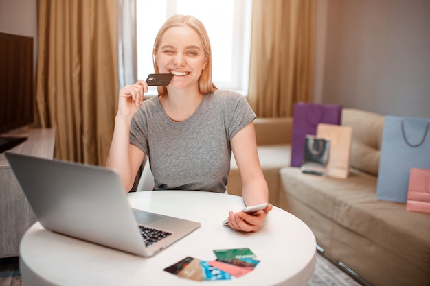 Young smiling shopper with credit card and smartphone