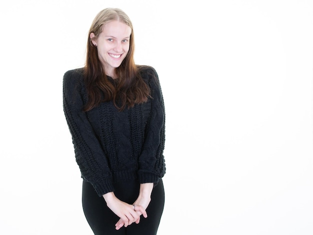 Young smiling shy woman blonde looking in camera on copy space white background