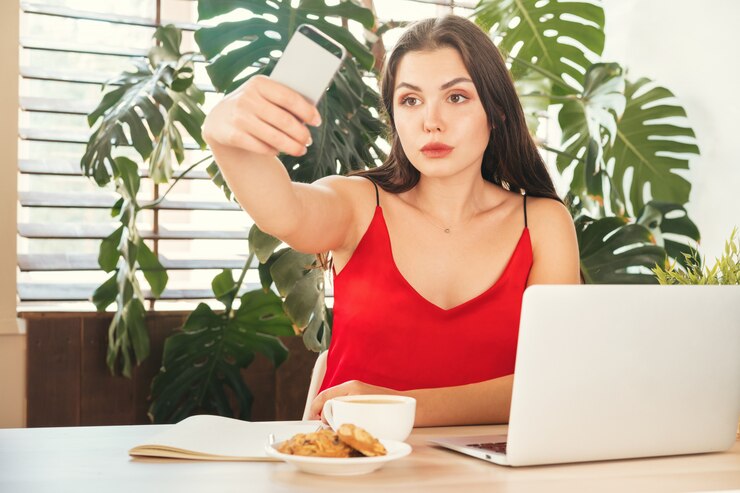 फोटो young smiling student girl doing selfie with her smartphone while at work
