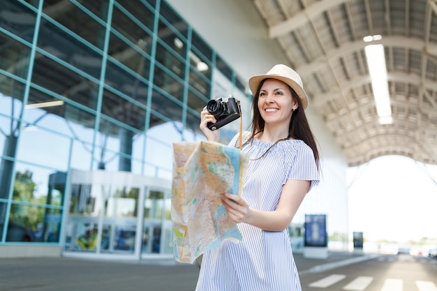 레트로 빈티지 사진 카메라, 국제 공항에서 종이지도를 들고 모자에 젊은 웃는 여행자 관광 여자