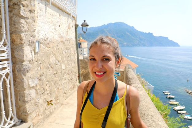 Young smiling traveler woman in Atrani village, Amalfi Coast in Italy