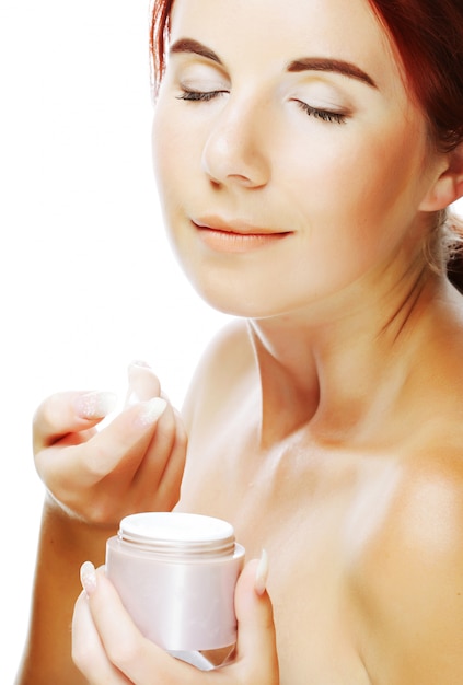 Foto giovane donna sorridente che applica crema sul suo fronte
