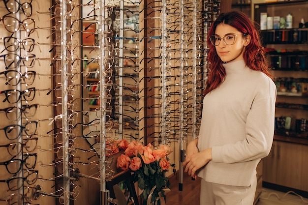 Young smiling woman choosing a new pair of prescription glasses at the eyewear store