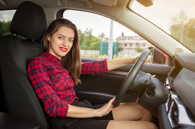 現代の車を運転して若い笑顔の女性