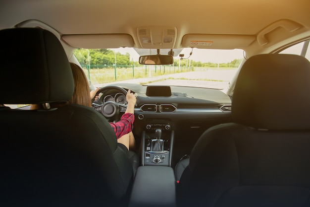 Giovane donna sorridente che conduce un'automobile moderna