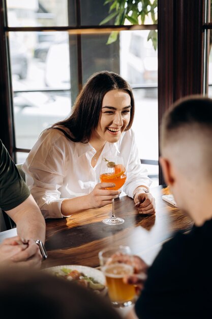 友人との休憩中にバーレストランでカクテルを楽しむ若い笑顔の女性 お祝いやパーティーのコンセプト