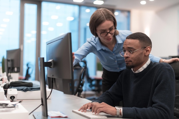 Young smiling woman explaining to serious african american coworker project strategy diverse startup