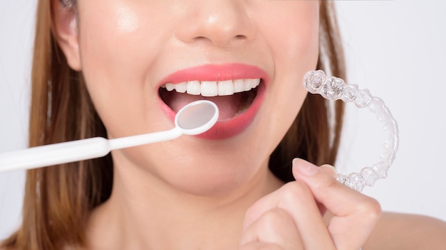 Фото Молодая улыбающаяся женщина, держащая брекеты invisalign в студии, стоматологическом здравоохранении и ортодонтической концепции