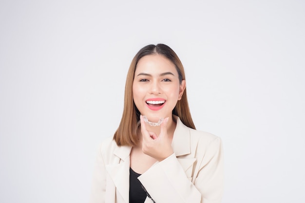 Young smiling woman holding invisalign braces in studio, dental healthcare and Orthodontic concept