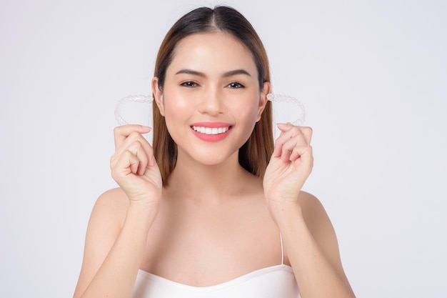 Photo young smiling woman holding invisalign braces in studio, dental healthcare and orthodontic concept