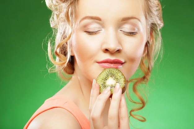 Young smiling woman holding kiwi