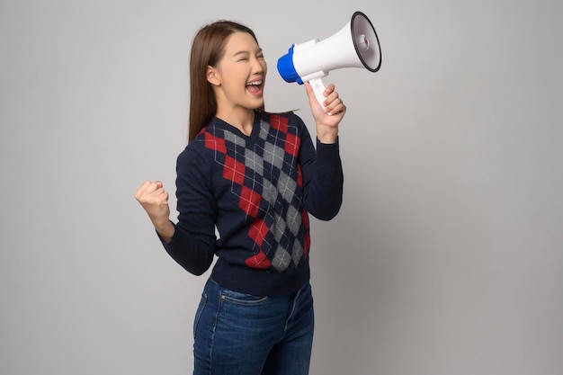 Young smiling woman holding megaphone over white background studiox9