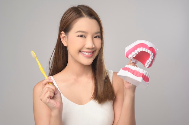 Young smiling woman holding toothbrush over white background studio