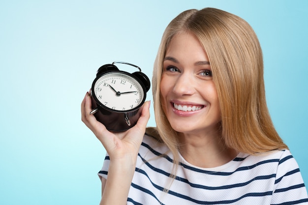 Young smiling woman holds black clock