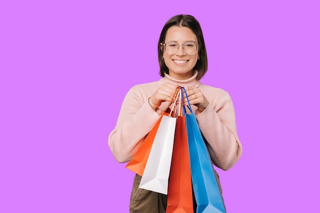 Young smiling woman is holding some shopping bags in front of her