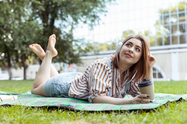 Foto giovane donna sorridente ascolta musica a quadri nel parco lifestyle