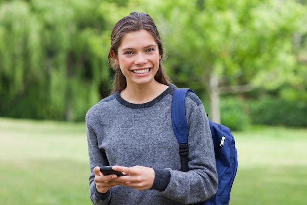 テキストを送信中にカメラを見て若い笑顔の女性