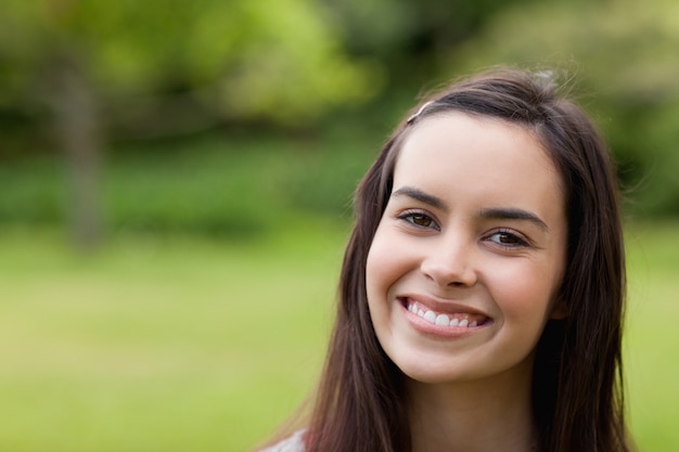 Young smiling woman looking at the camera while standing up in a park