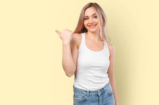 Young smiling woman pointing to copy space isolated on color background