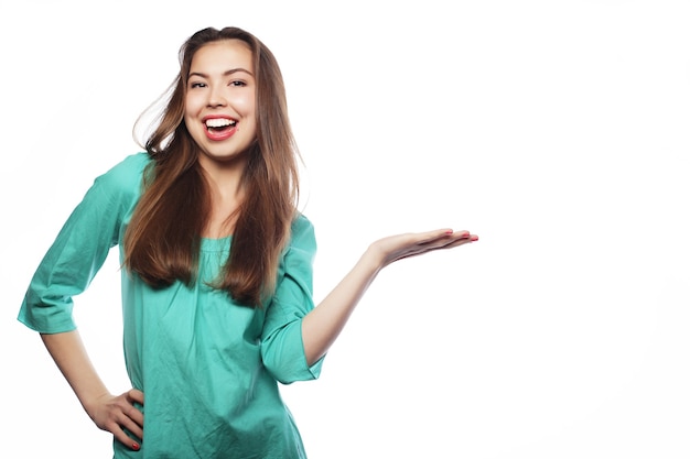 Young smiling woman points a hand with positive facial expression. isolated on white