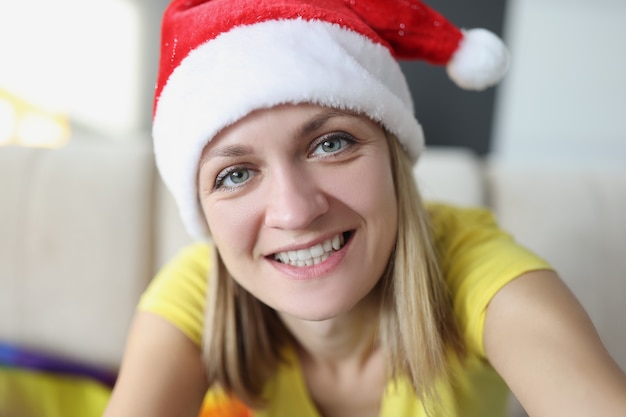 셀카를 찍고 빨간 산타 클로스 모자에 젊은 웃는 여자. 새해 복 많이 받으세요 그리고 메리 크리스마스 개념