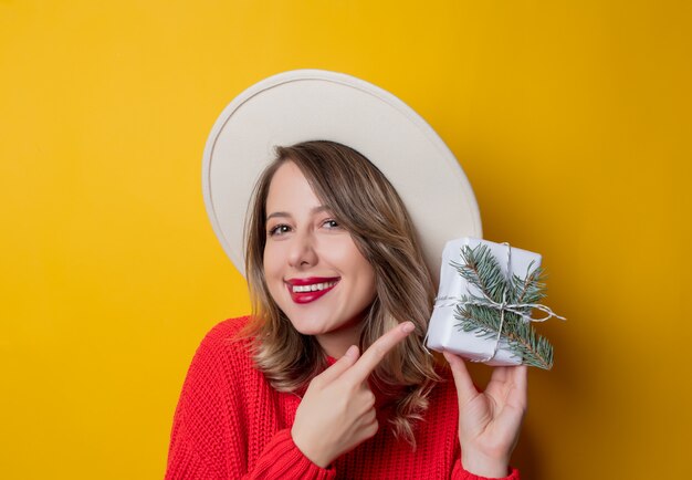 Young smiling woman in red sweater with gift box