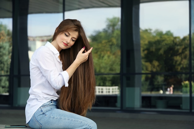 Young smiling woman straightens her long hair