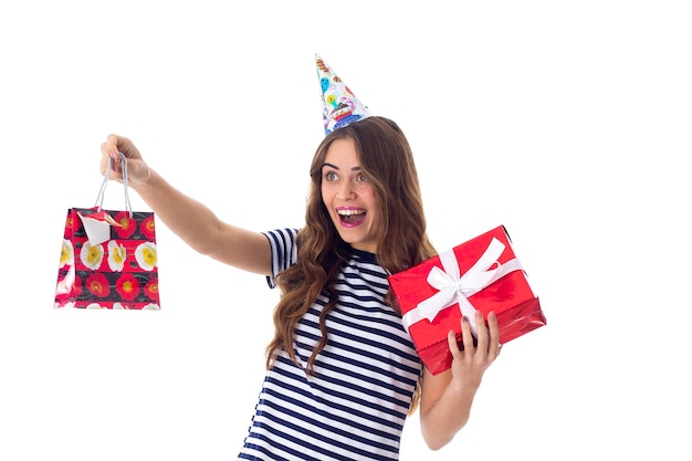 Young smiling woman in stripped Tshirt and celebration cap holding presents in studio