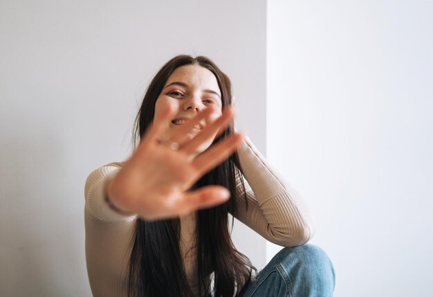 Young smiling woman teenager girl with dark long hair in jeans in her room at the home