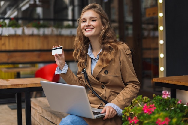 Young smiling woman in trench coat happily 