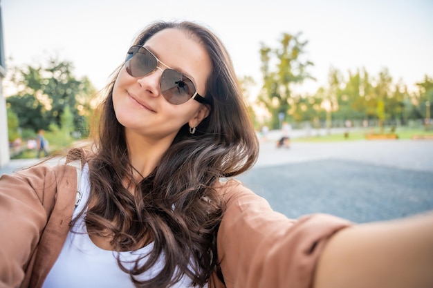 Young smiling woman in trendy summer clothes happy model posing in the street at sunny day makes pov