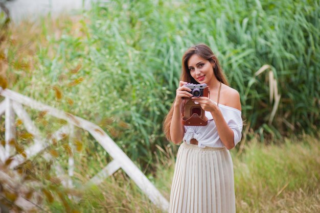 Young smiling woman in vintage style clothes with retro camera 