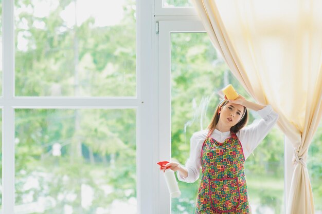 Young Smiling Woman Washing Window with Sponge