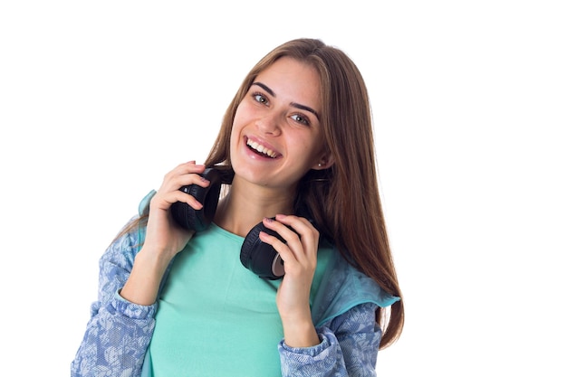 Young smiling woman with long brown hair in blue shirt in black headphones in studio