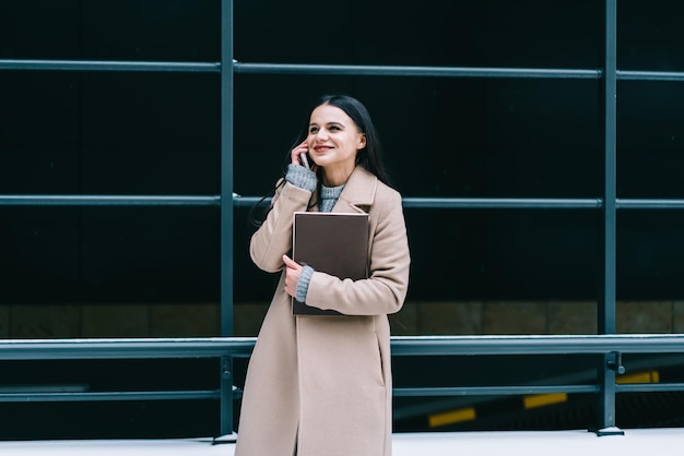 スマートフォンで話しているメモ帳と若い笑顔の女性