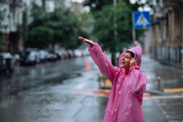 写真 雨の日を楽しみながらレインコートを着た若い笑顔の女性